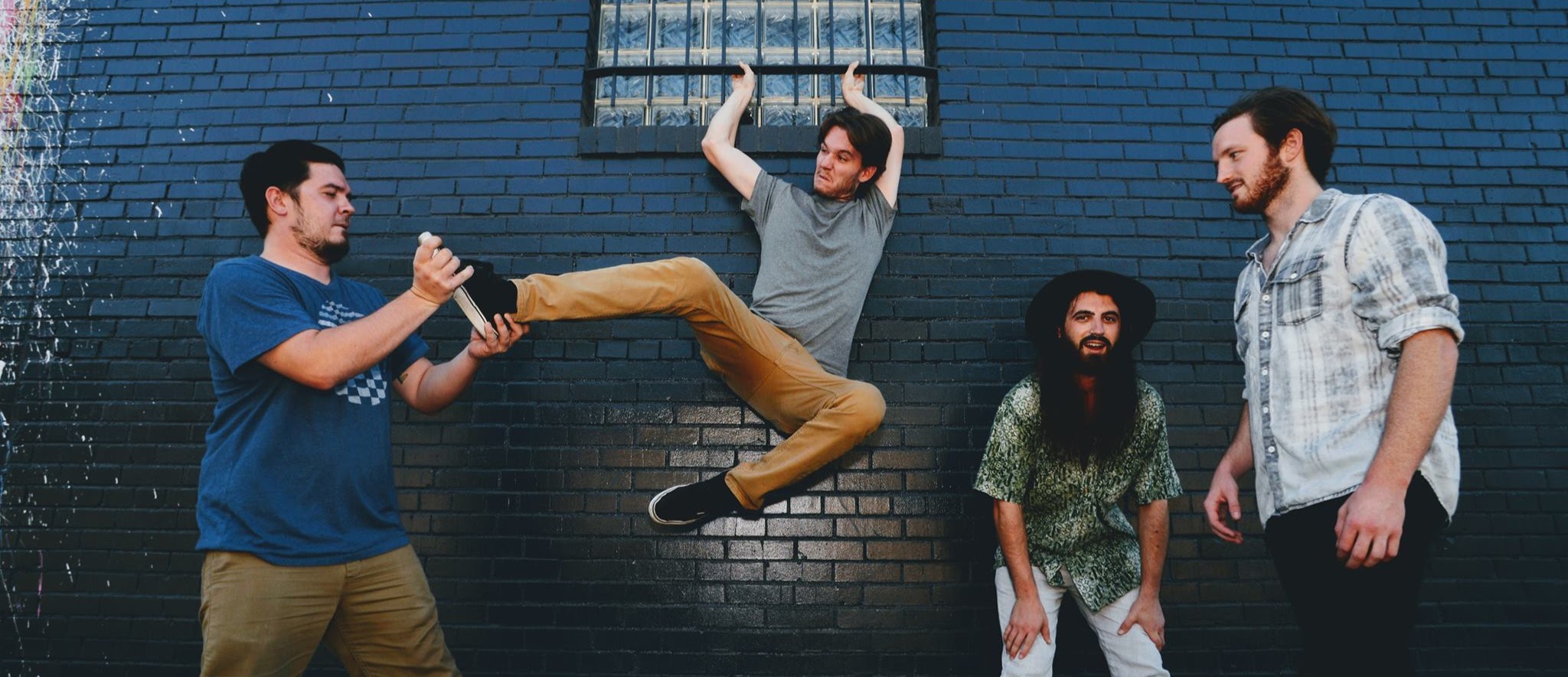 band hanging out in front of blue brick wall